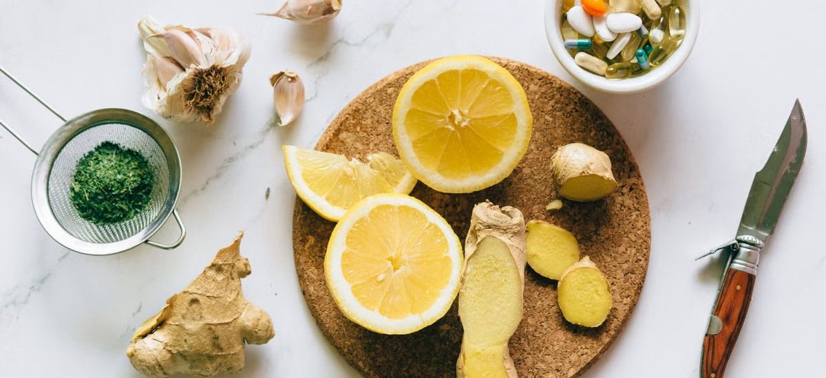 Flat lay of natural remedies including lemon, ginger, and garlic alongside pills.